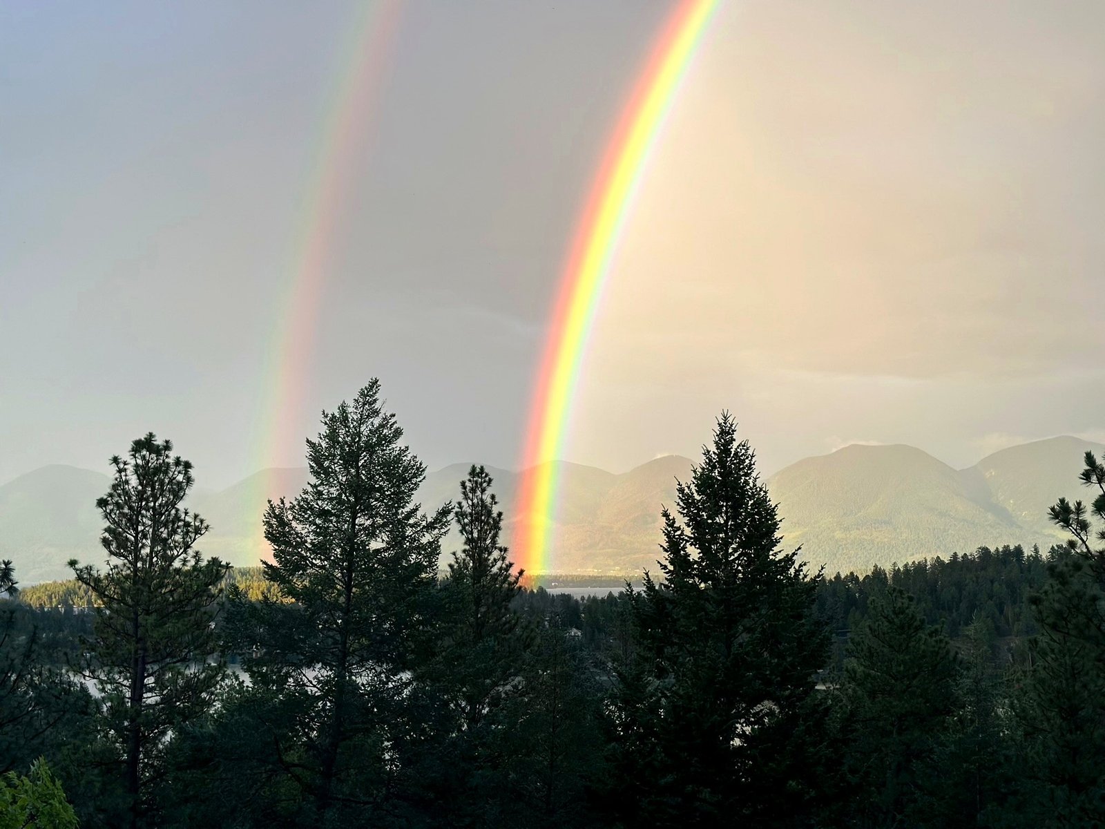 Rainbow arching over Eagle's Bluff estate and Flathead Lake, Montana